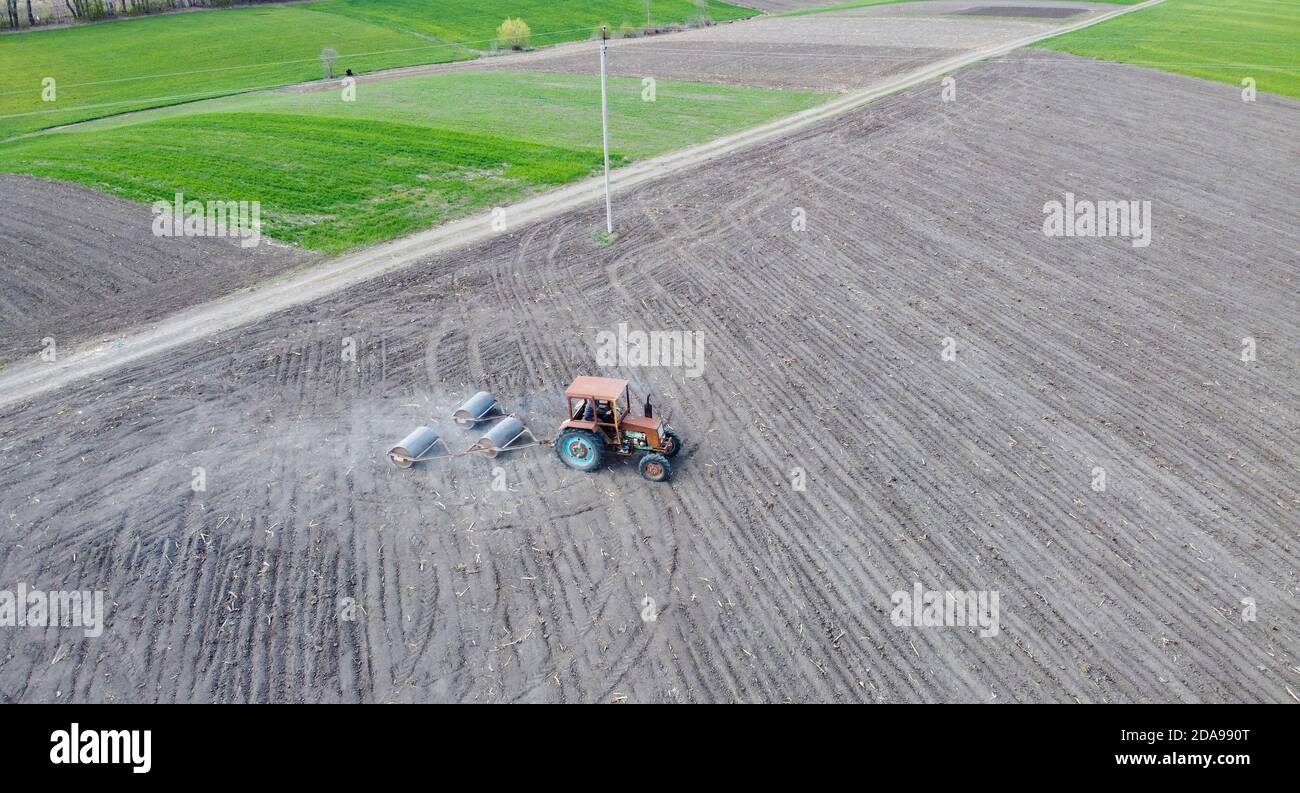 Un vecchio trattore nel campo aratura il mais appena seminato Foto Stock