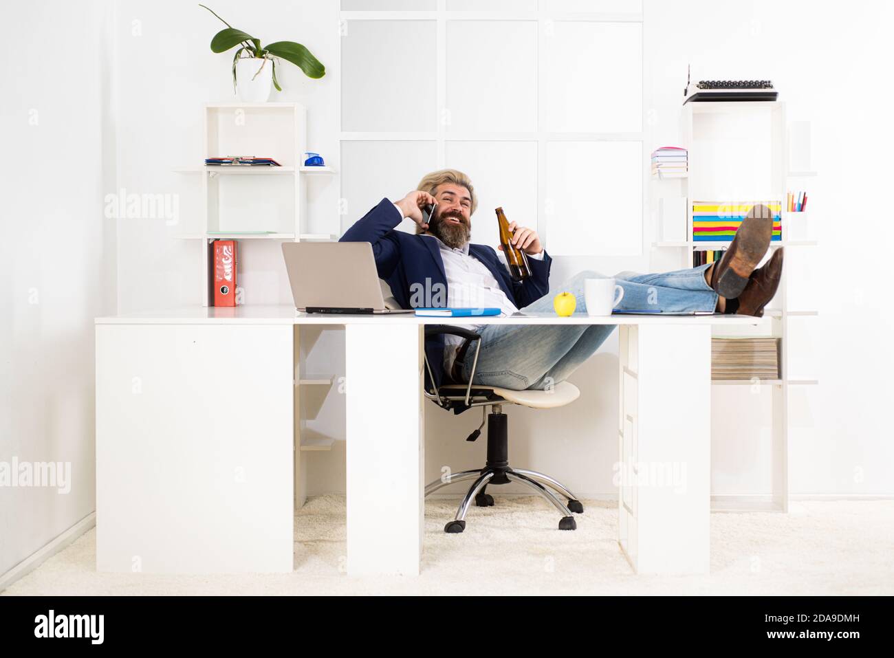 L'uomo d'affari ha finito la giornata di lavoro con l'alcol. Uomo ubriaco divertente che tiene una bottiglia di birra. Foto Stock