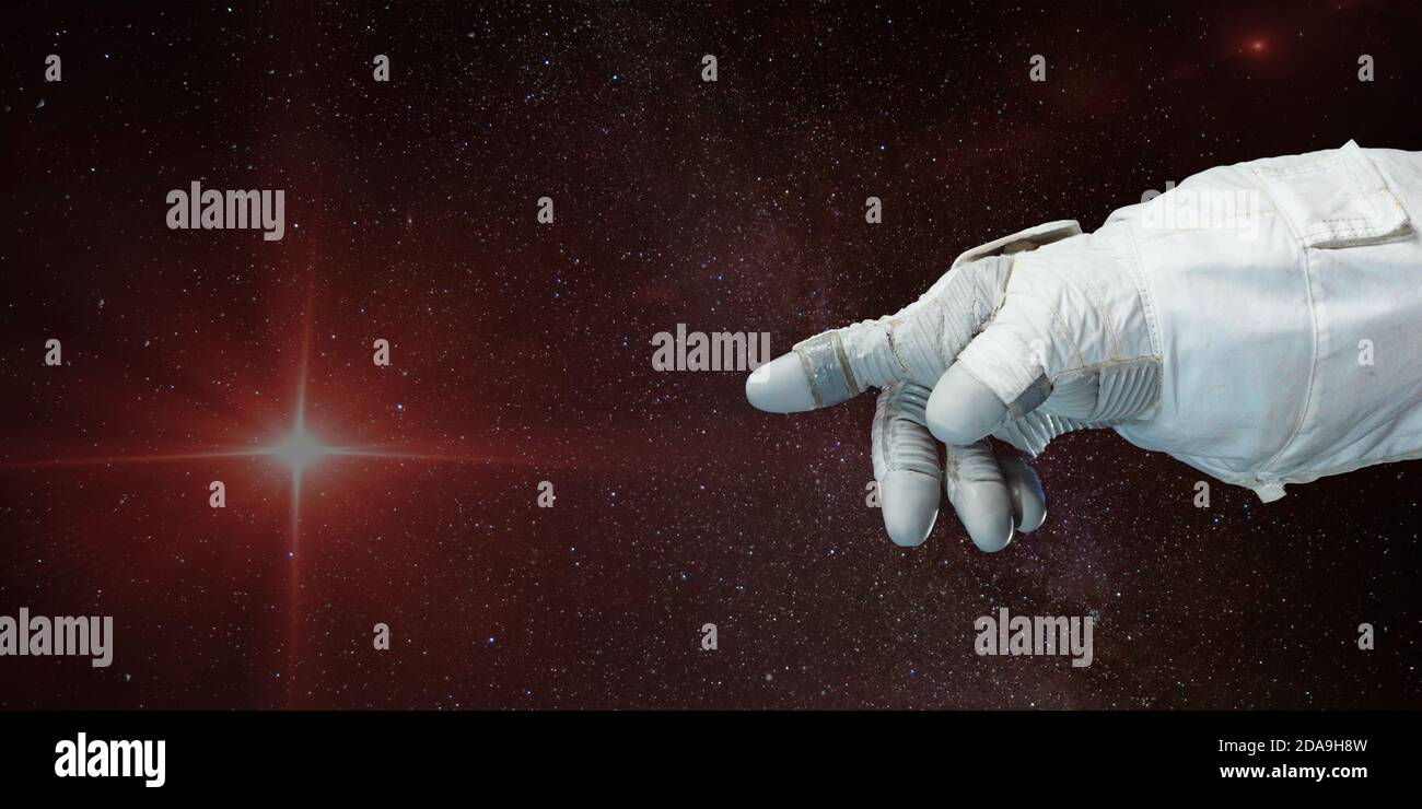 Mano astronauta che punta verso la stella con sfondo di profondo spazio. Elementi di questa immagine forniti dalla NASA. Foto Stock