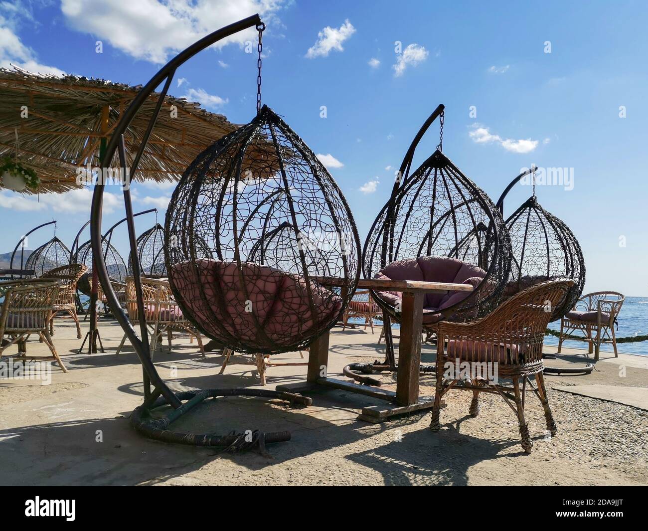 Terrazza esterna con tavolo vuoto in legno e sedia con vista mare. Sedie a sdraio, tavolo in terrazza, ombrellone dal sole. Foto Stock