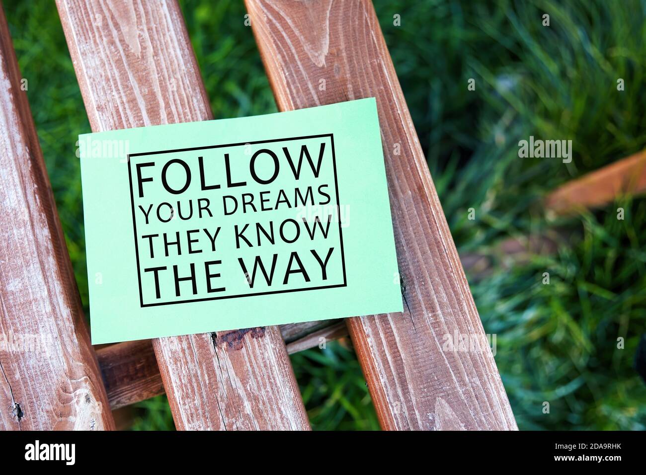 Segui i tuoi sogni conoscono il modo ispirato vita citazione testo scritto su carta su una panchina in un giardino. Foto Stock