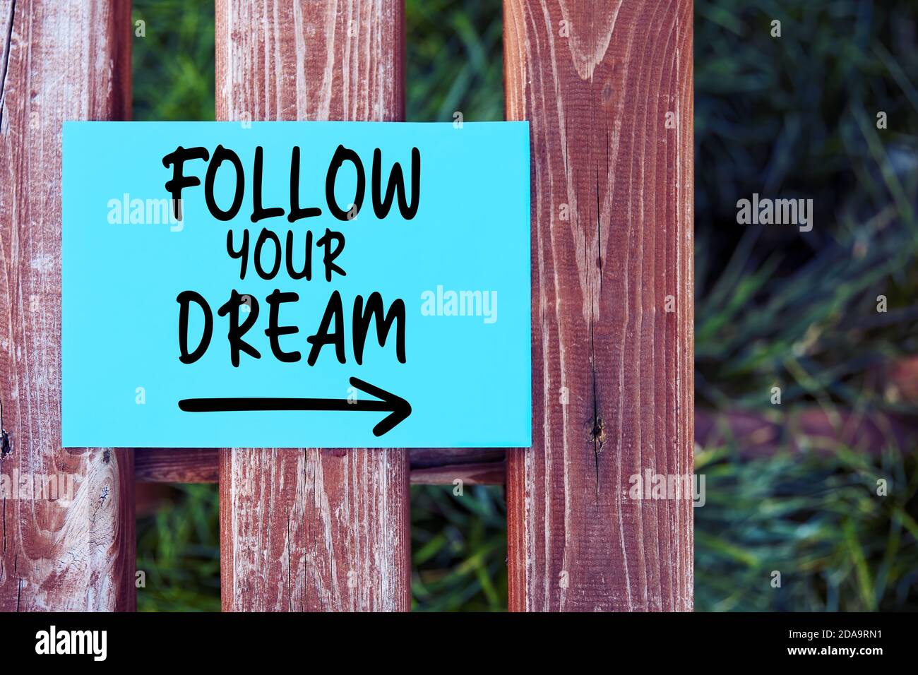 Segui il tuo testo di citazione ispiratrice del sogno scritto su carta su una recinzione in un giardino. Foto Stock