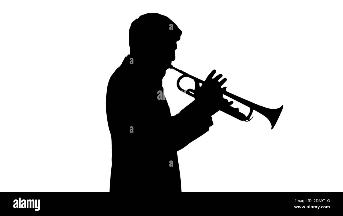 Silhouette giovane uomo in tuta che suona una tromba mentre cammina. Foto Stock