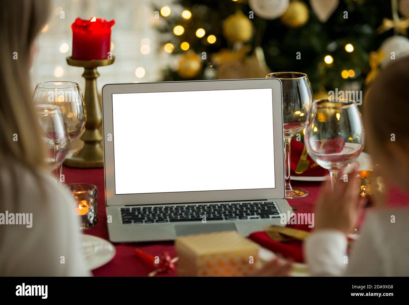 Una famiglia felice con un bambino festeggia il Natale con i suoi amici in videochiamata utilizzando la webcam. La famiglia saluta i loro parenti alla vigilia di Natale Foto Stock