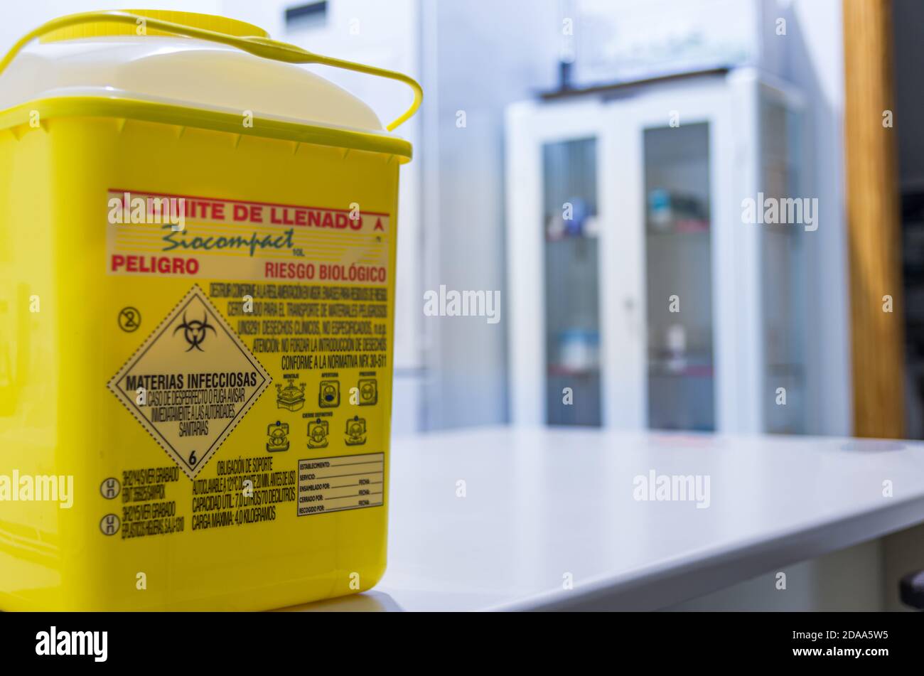 Contenitore per rifiuti biologici su un tavolo dell'ospedale e sullo sfondo del mobile per medicinali. Foto Stock