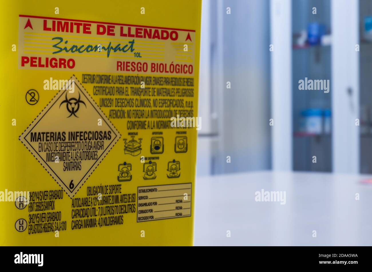 Contenitore per rifiuti biologici su un tavolo dell'ospedale e sullo sfondo del mobile per medicinali. Foto Stock