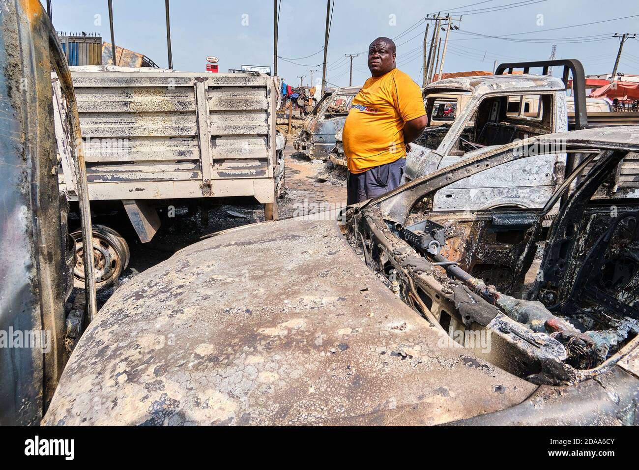 Il Sig. Kazeem si pone per una foto in un luogo in cui molti dei suoi veicoli sono stati danneggiati a seguito di un'esplosione dopo che una petroliera che trasportava carburante si è schiantata al Ponte di Kara lungo l'autostrada Lagos-Ibadan. Testimoni oculari sostengono che 3 persone sono state bruciate a morte, veicoli parcheggiati presso una stazione degli autobus e alcuni in vendita a molto sono stati bruciati nell'incidente che è accaduto intorno alle 2 del mattino dopo che una petroliera a carburante è esploso dopo aver perso i suoi pneumatici. Lagos, Nigeria. 7 novembre 2020. Foto Stock