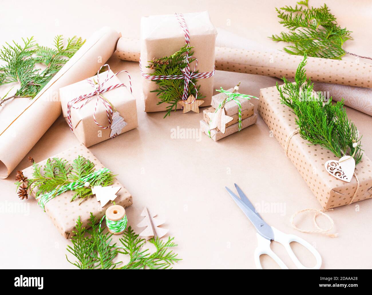 Preparandosi per le feste di Natale. Confezione regalo in carta artigianale e decorazione con ramo di thuja Foto Stock