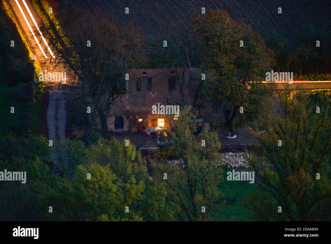 Un tempo di esposizione di luci auto che scagliano dietro un vecchio fienile, nel borgo medievale francese in cima alla collina di Cordes-sur-Ciel. Foto Stock