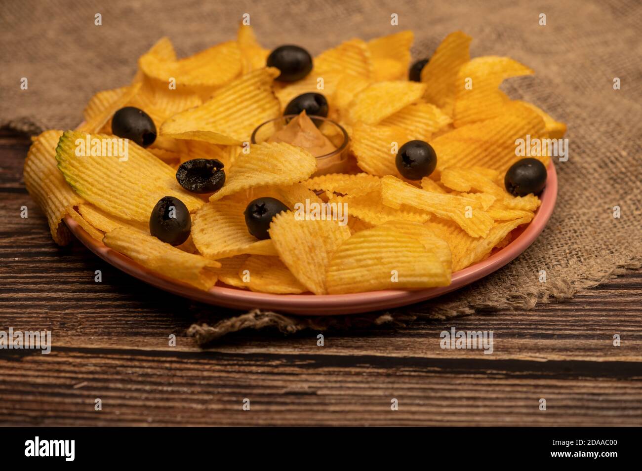 Patatine croccanti e deliziose con salsa di senape e olive su un panno di casa grossolano. Primo piano Foto Stock