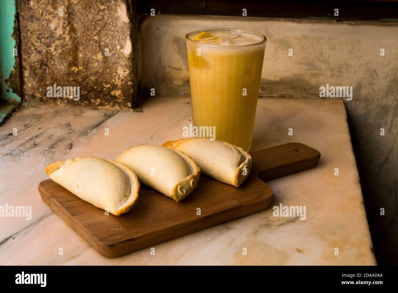 Empanadas argentini al forno tradizionale, dolci salati con ripieno di carne di manzo e verdure su fondo di legno con salsa piccante e ghiaccio limone Foto Stock