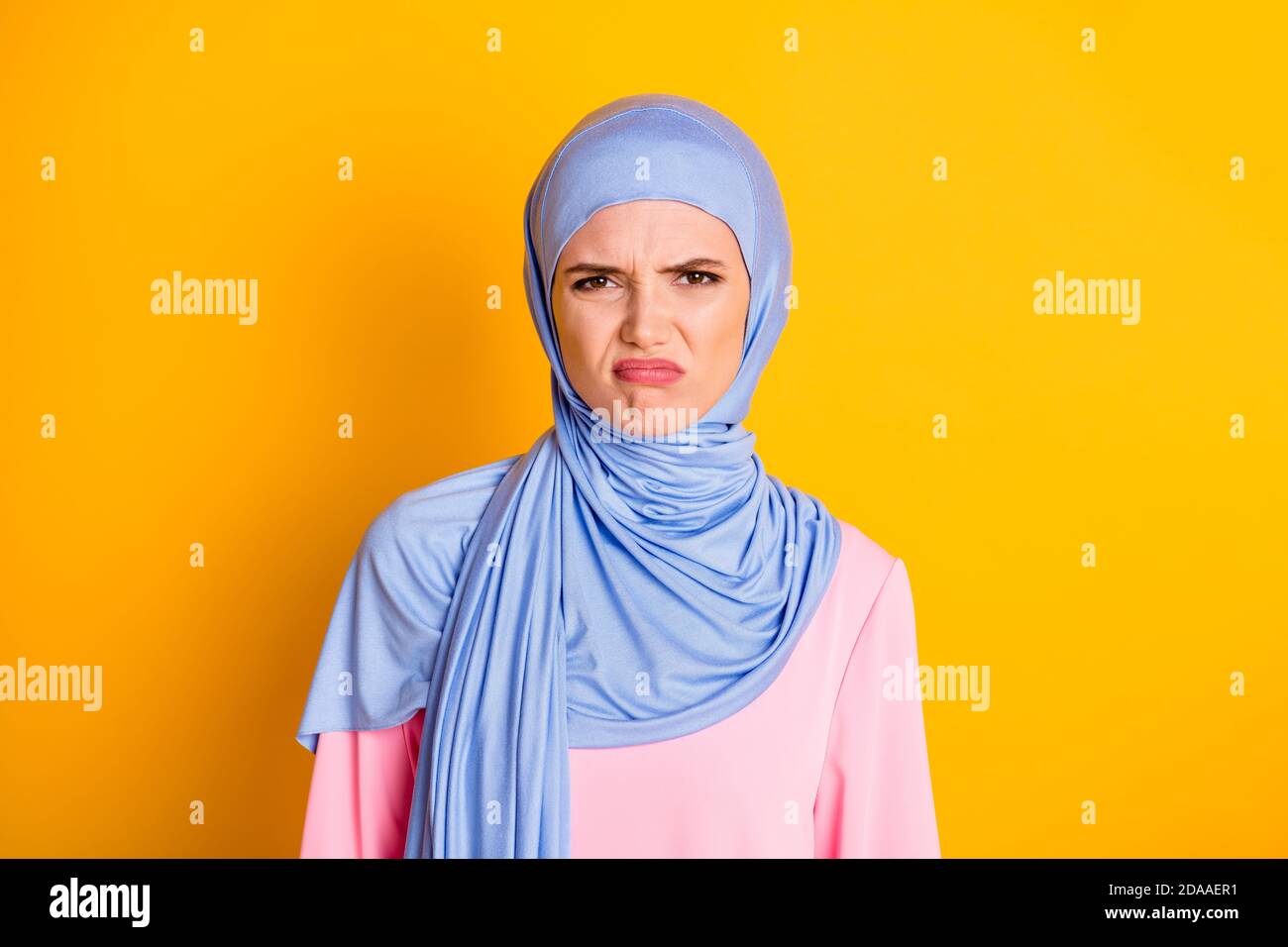 Primo piano ritratto di attraente muslimah capricciosa dispiaciuto indossando hijab perseguire labbra isolate su sfondo giallo brillante Foto Stock