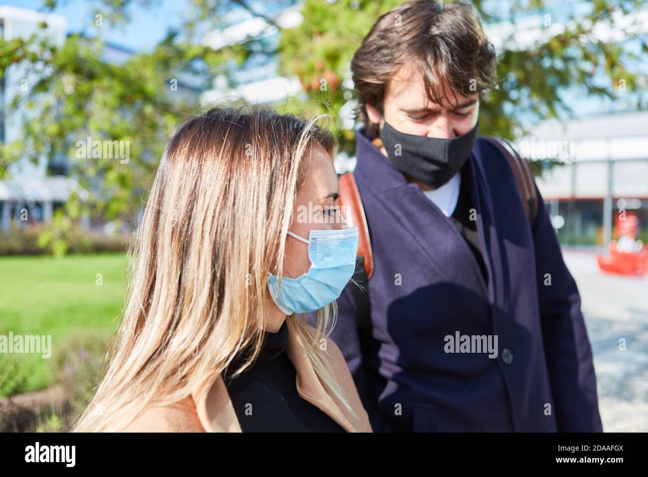 Passers-by in città con maschere per il viso a causa di Covid-19 pandemia Foto Stock