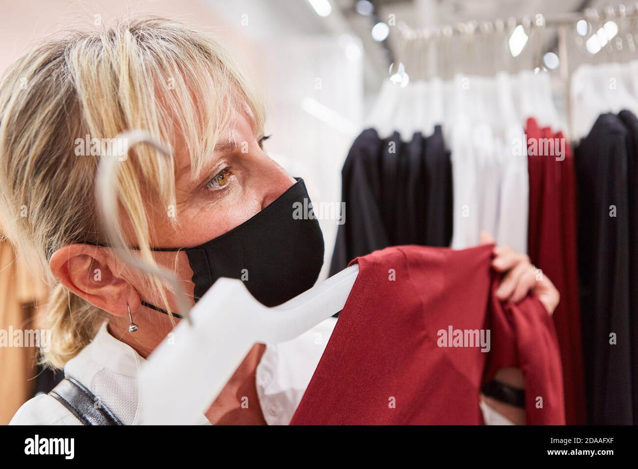 Cliente con maschera facciale in una boutique quando acquista moda Durante la pandemia di Covid-19 Foto Stock