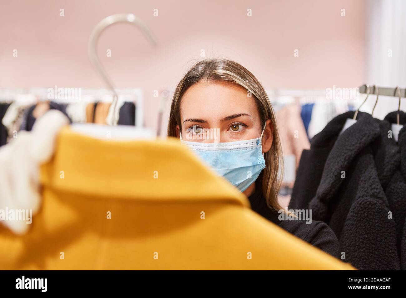 Donna come cliente con maschera facciale in un modo Negozio durante lo shopping durante la pandemia Covid-19 Foto Stock