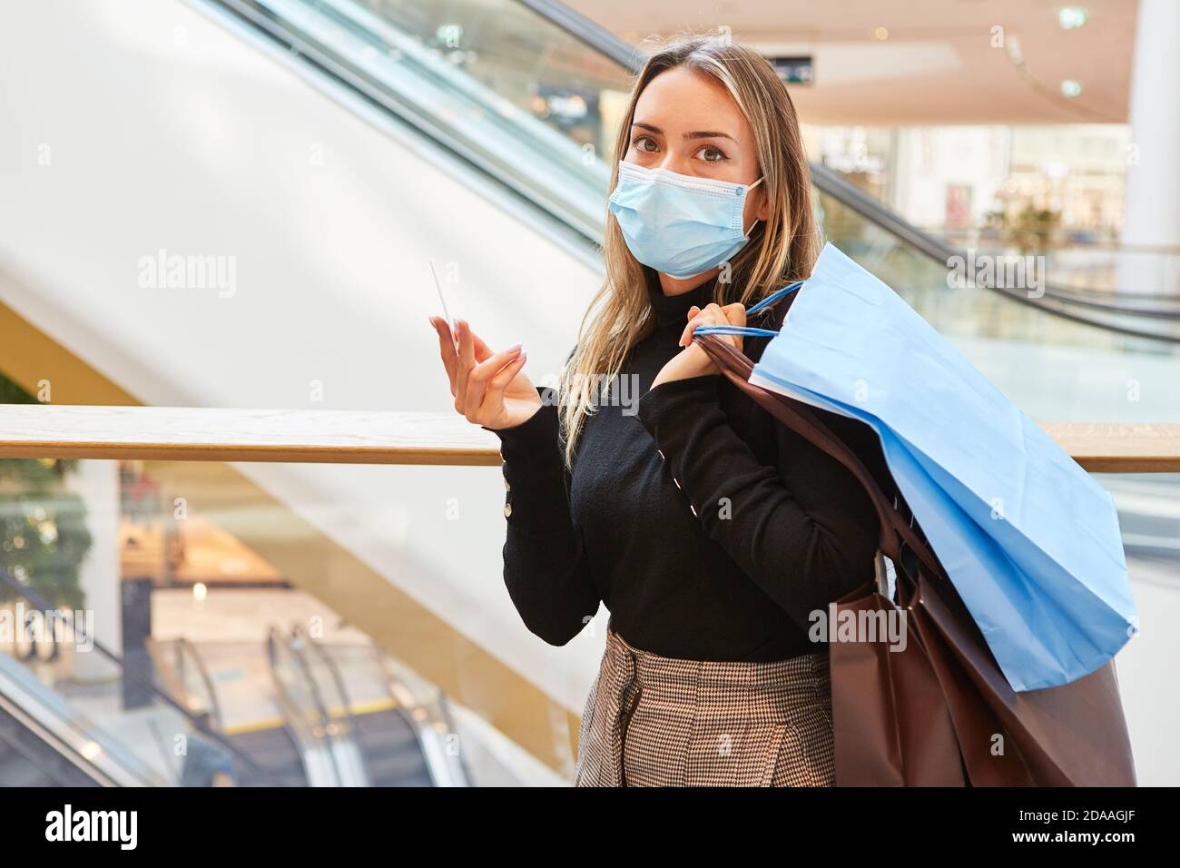 Donna come cliente con un sacco di borse per la spesa e. Maschera facciale a causa di Covid-19 durante lo shopping Foto Stock