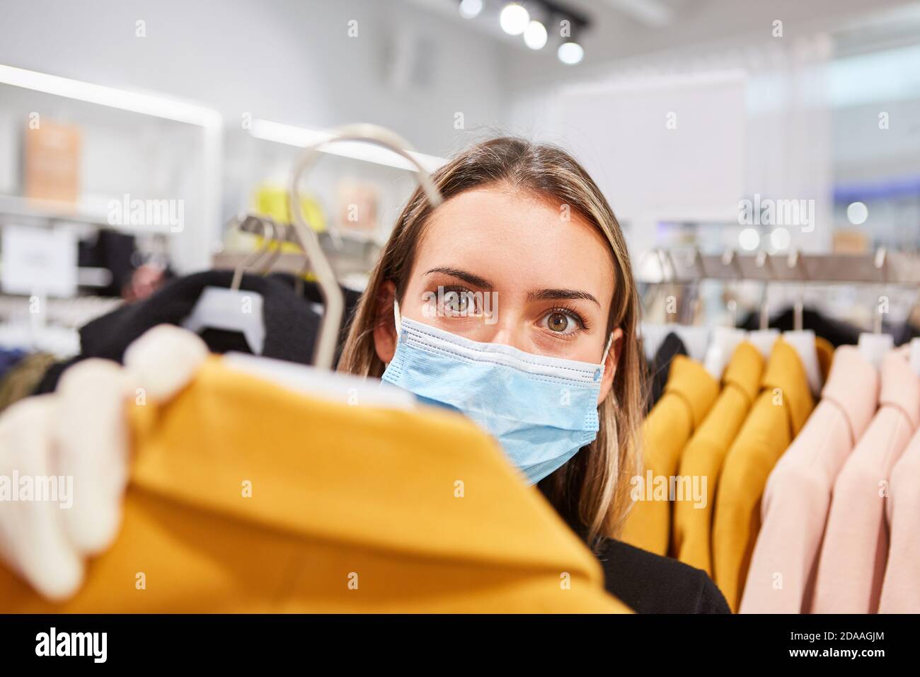Cliente con maschera a causa della pandemia di Covid-19 in una boutique durante lo shopping Foto Stock