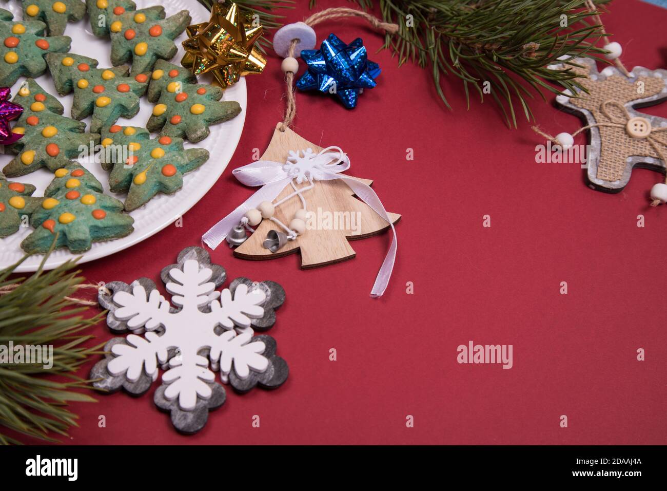 Pan di zenzero di Natale decorato con glassa sotto forma di alberi di Natale con decorazione di Natale su uno sfondo rosso.primo piano, spazio di copia. Orizzontale Foto Stock