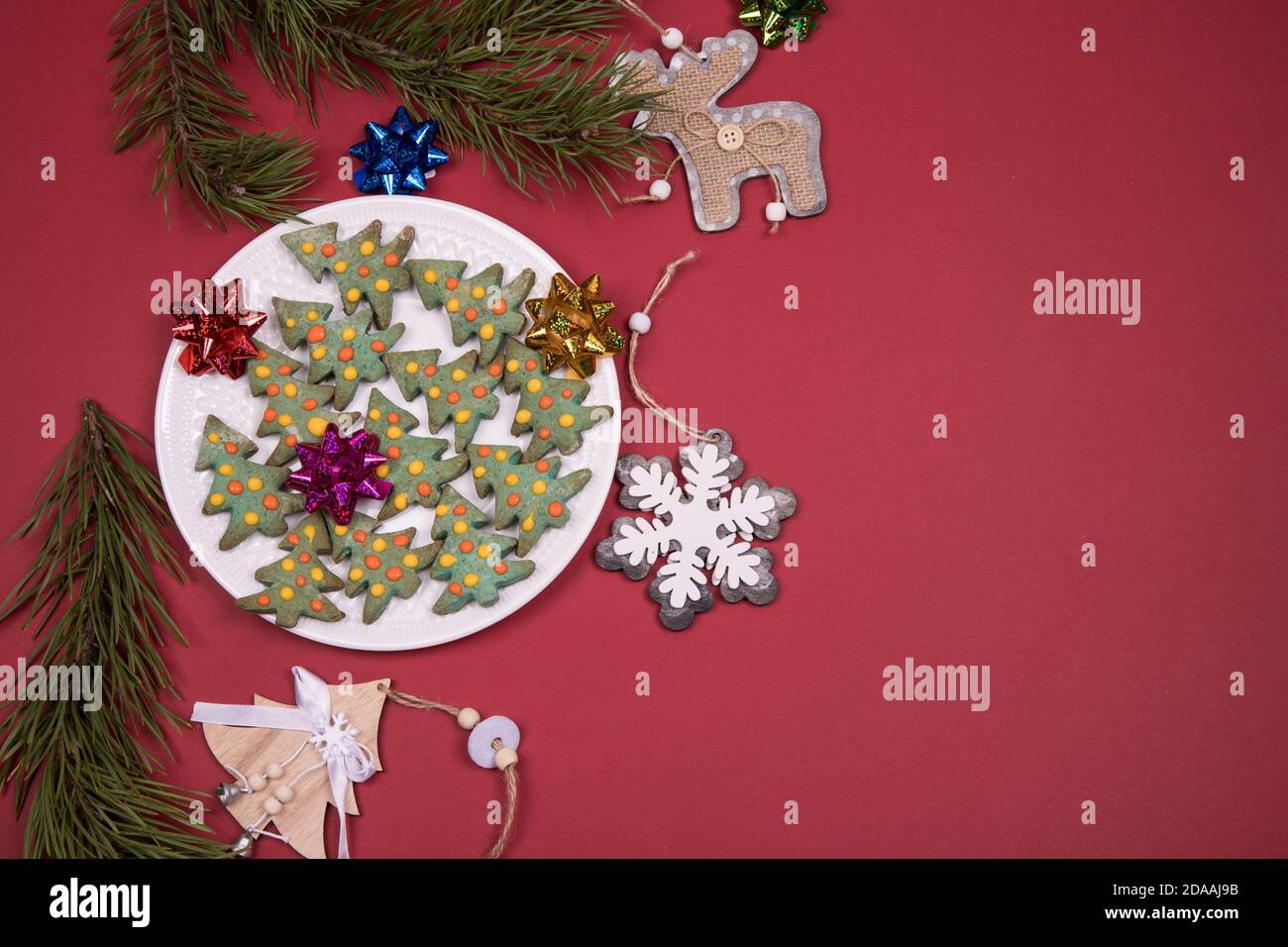 Decorato con gingerbread glassare Natale sotto forma di alberi di Natale fatti in casa con decorazioni natalizie su sfondo rosso. Primo piano, spazio per la copia Foto Stock