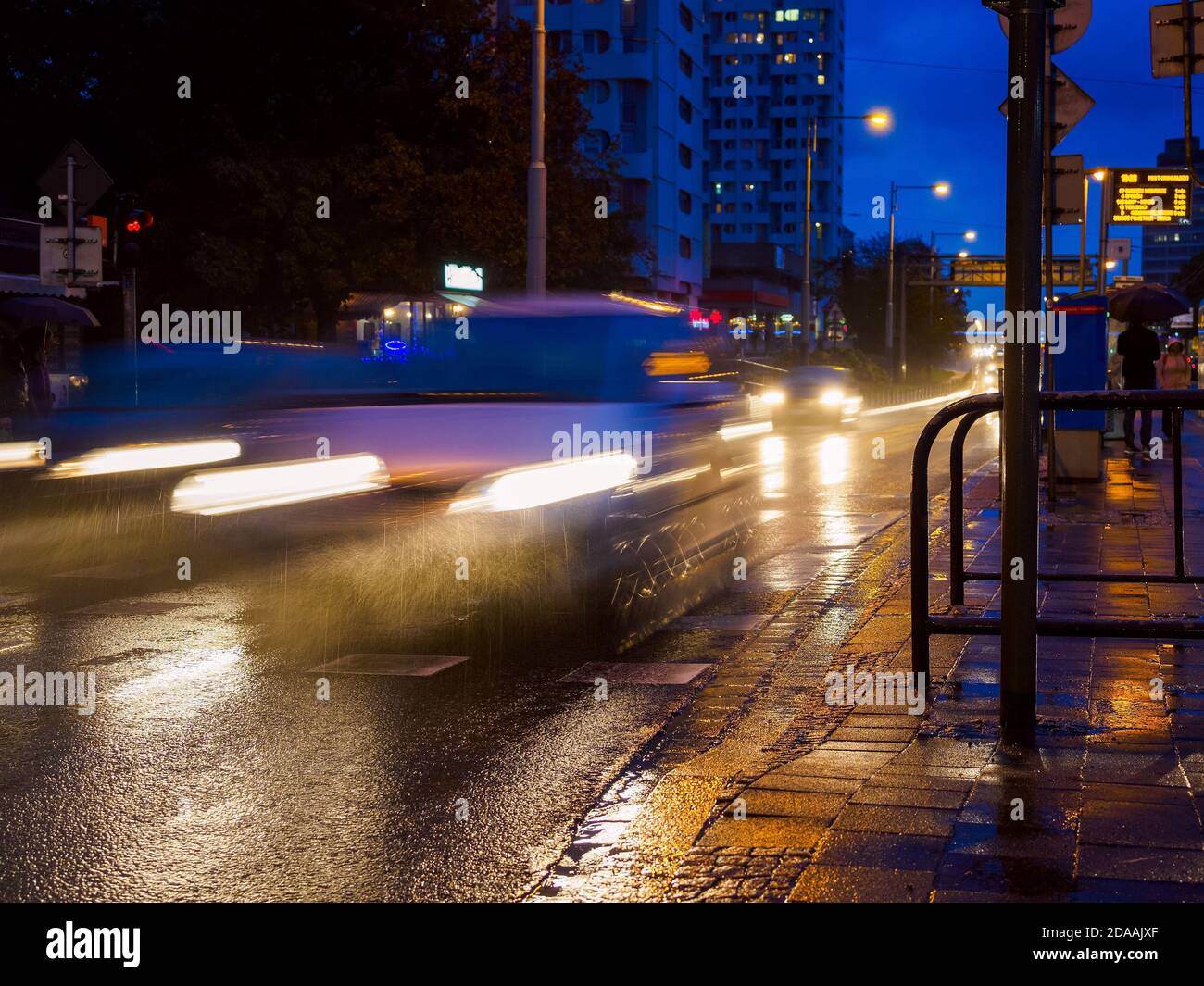 strada della città piovosa di notte, traffico notturno su strada bagnata durante la pioggia, luci di strada riflesse in pozzanghere. Foto Stock