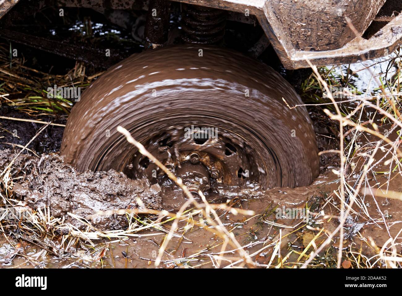 Veicolo bloccato nel fango. Closeup ruota rotante della macchina scivola nel fango nella palude. Foto Stock