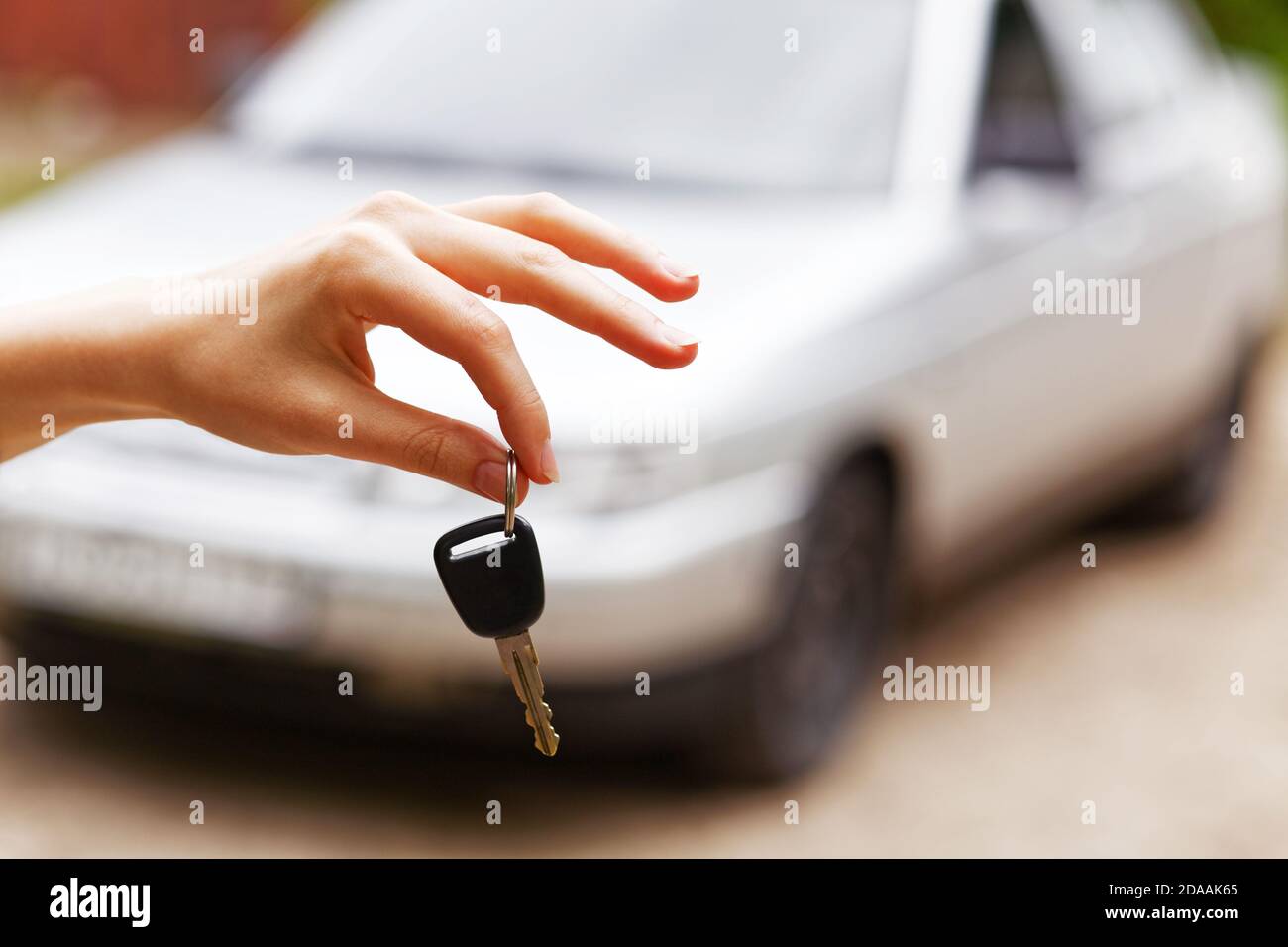 Le donne tengono la chiave dell'auto contro l'auto su sfondo sfocato Foto Stock