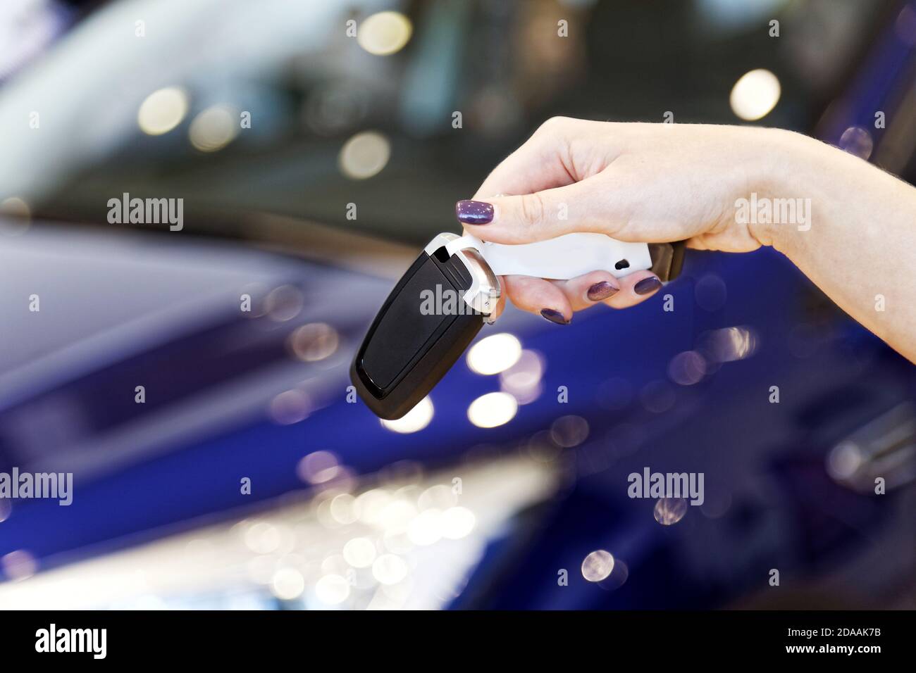 Le donne tengono la chiave dell'auto contro l'auto su sfondo sfocato Foto Stock