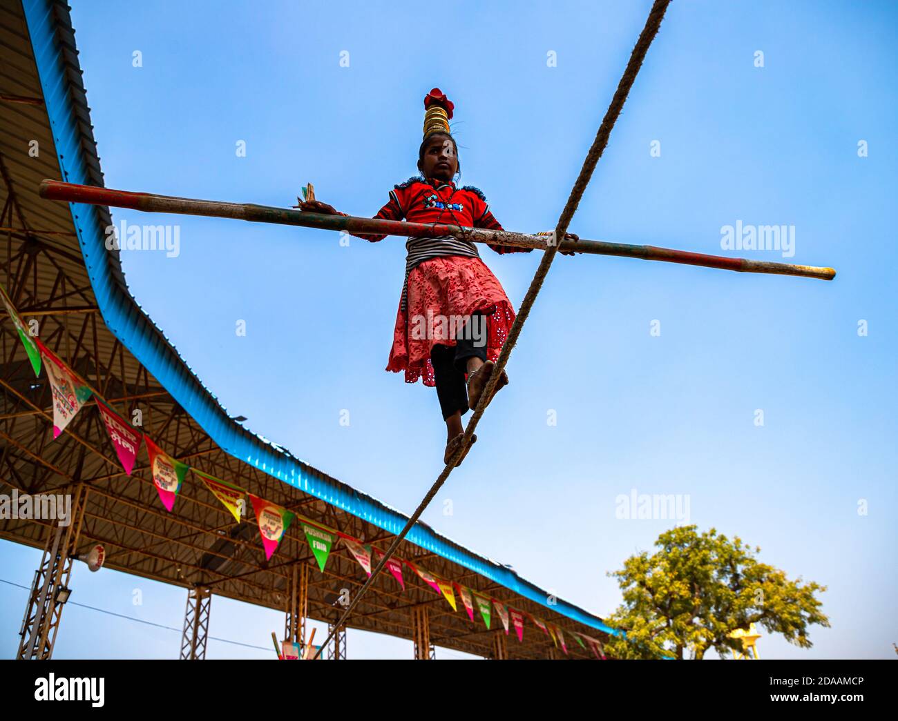 una ragazza indiana esegue acrobazie di strada camminando sulla corda stretta al festival del cammello pushkar. Foto Stock