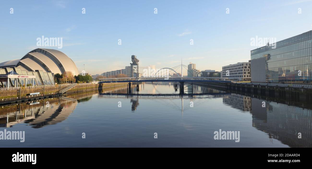 Un fiume piatto e tranquillo Clyde che attraversa il centro di Glasgow con i suoi numerosi punti di riferimento, tra cui il Ponte di Bell, la gru di Finnieston e Armadillo. Foto Stock