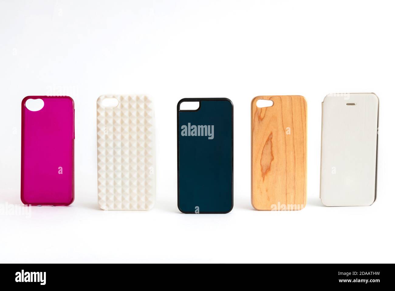 Pila di coprischiera in plastica multicolore per cellulare. Scelta di accessori per custodia protettiva per smartphone. Il telefono in silicone si trova sul dorso bianco Foto Stock