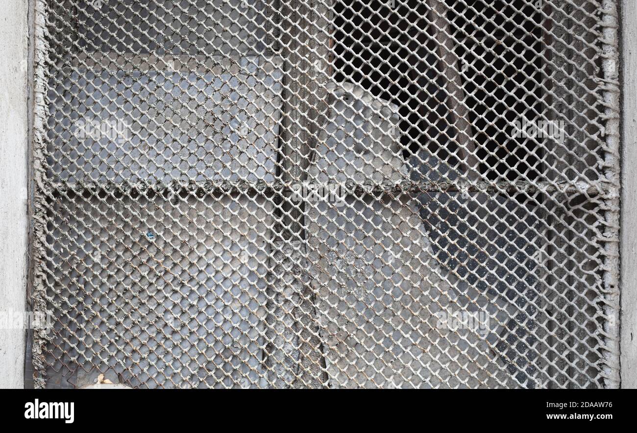 Vecchia rete metallica su una finestra rotta. Vetro rotto dietro una rete  metallica arrugginita Foto stock - Alamy
