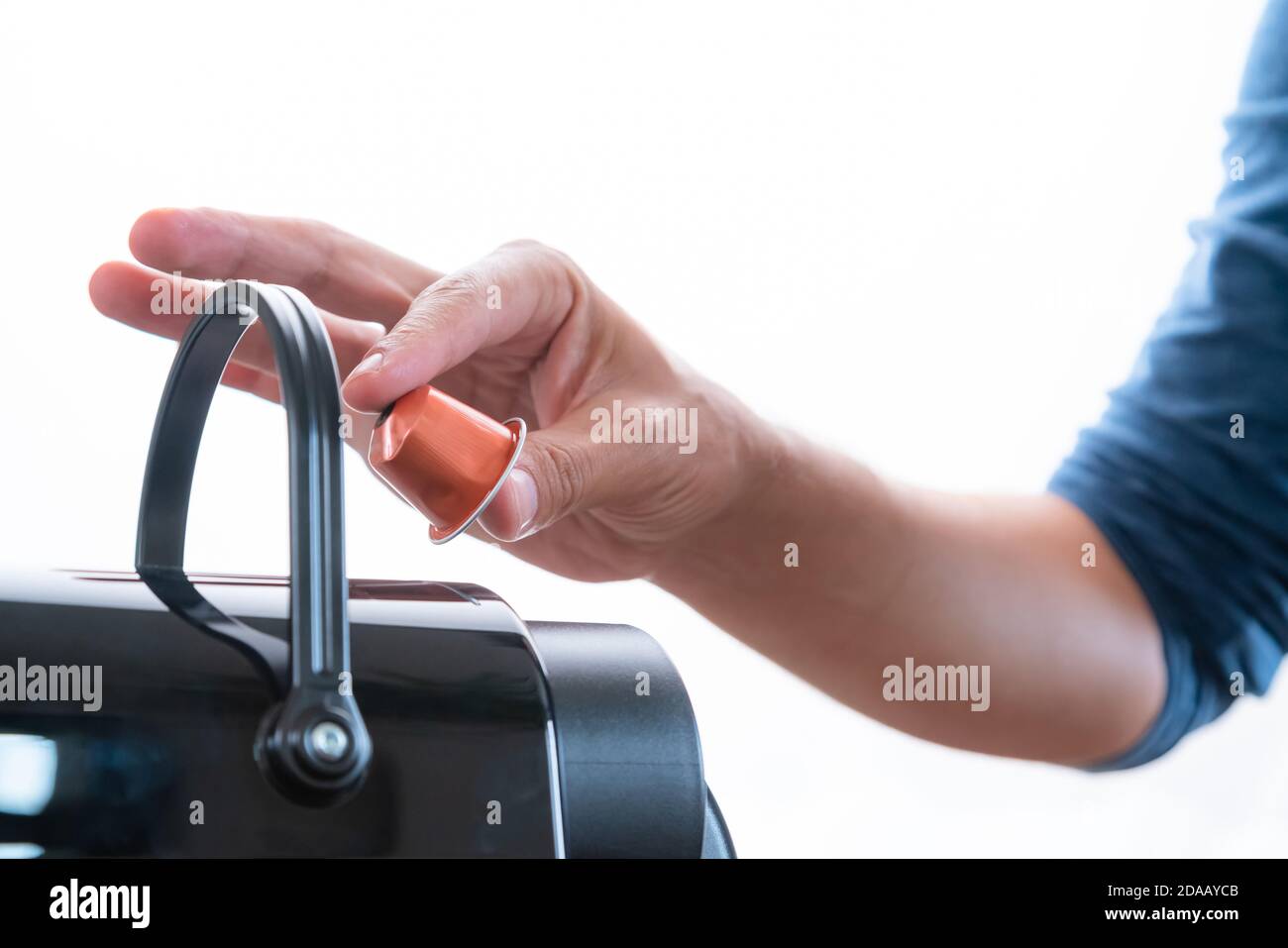 Primo piano di una mano che inserisce una capsula in una macchina da caffè a casa. Concetto di pausa caffè. Foto Stock