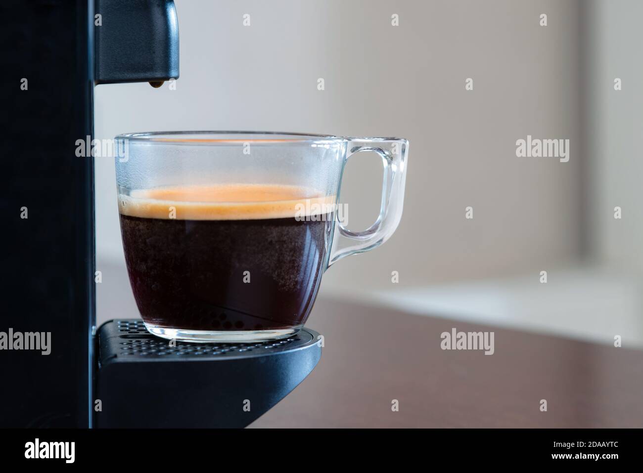 Primo piano con l'espresso rinfrescante che versa la macchina a capsule in una tazza a casa. Concetto di pausa caffè. Foto Stock