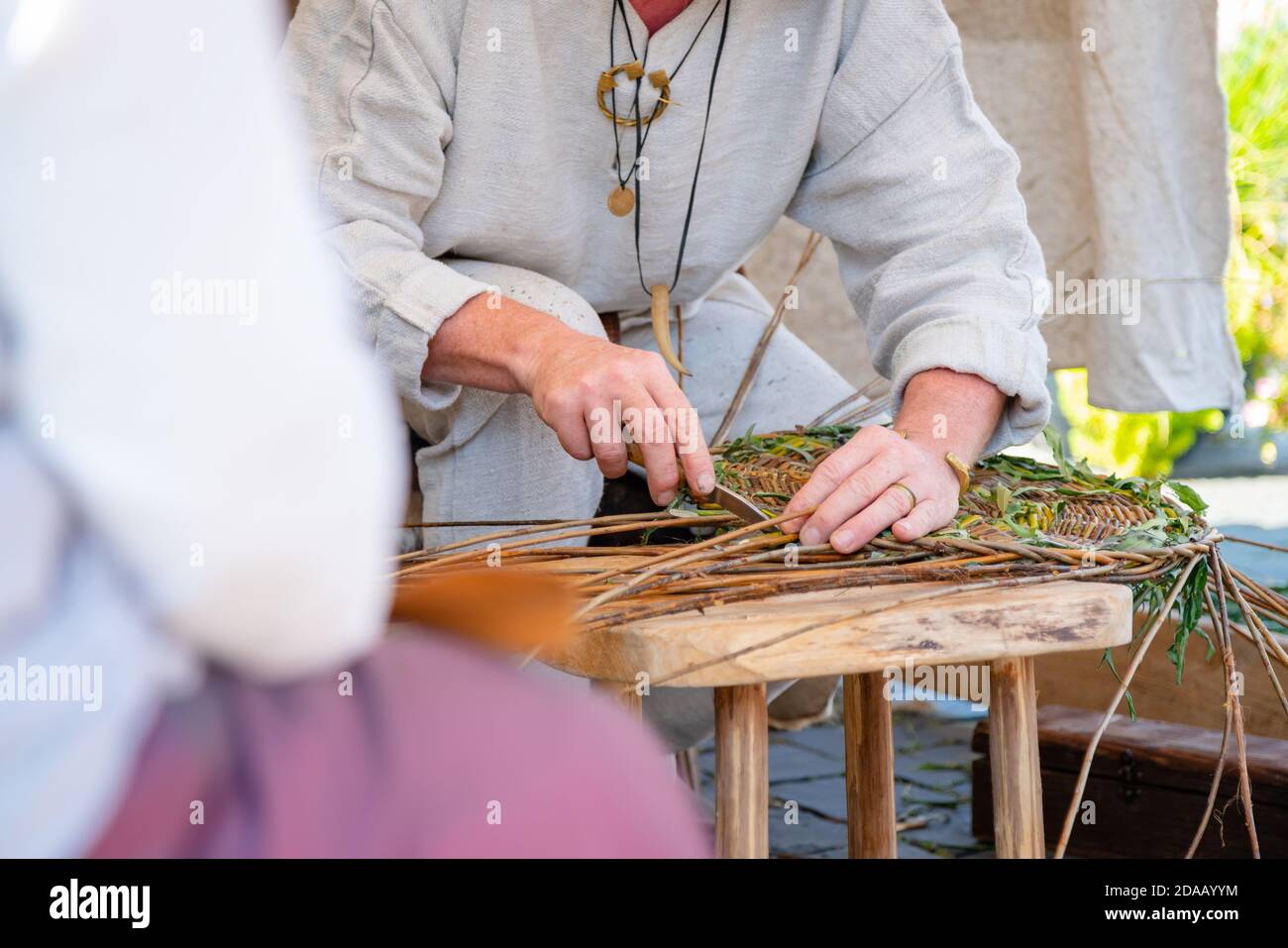 Primo piano di artigiano che indossa abiti rurali che fanno cesto di vimini Foto Stock