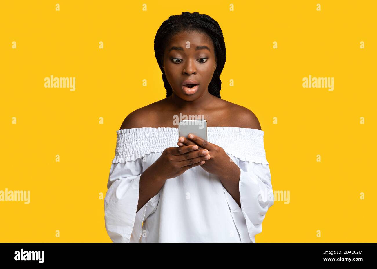 OMG. Donna nera sorpresa guardando lo schermo dello smartphone con espressione del volto sconvolto Foto Stock
