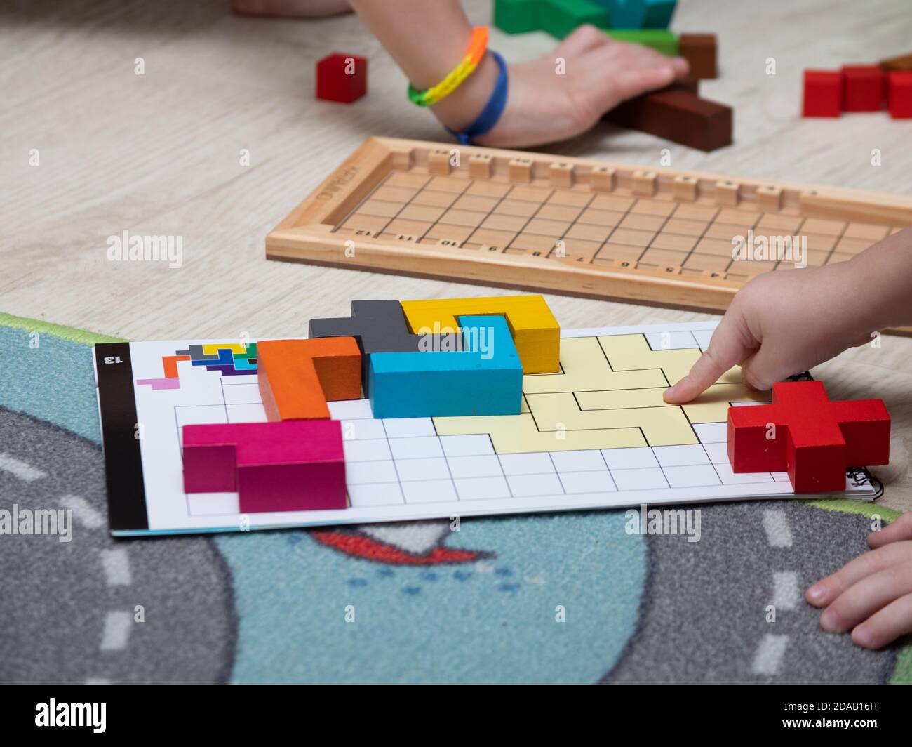 I bambini giocano un gioco da tavolo. Giochi educativi per bambini. I bambini mettono i blocchi colorati per riempire tutte le celle vuote Foto Stock