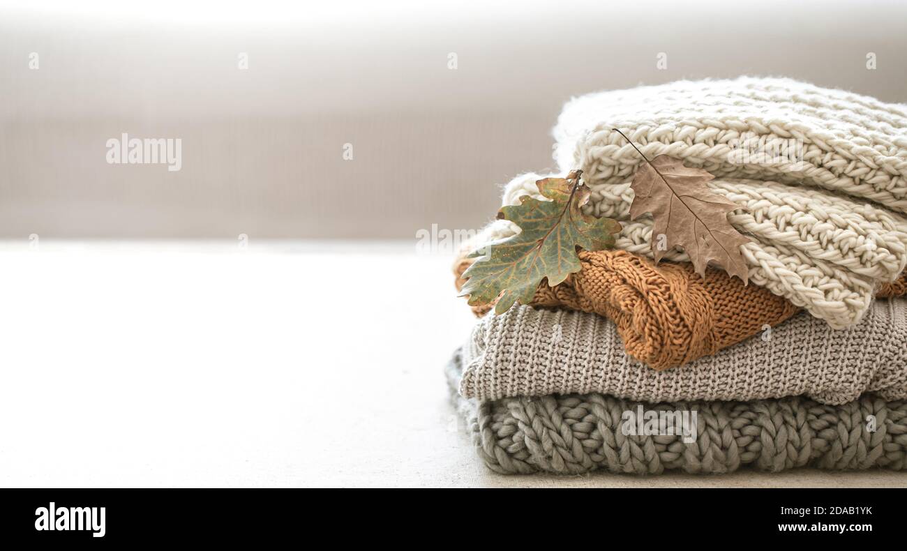 Pila di articoli in maglia calda dal guardaroba autunnale primo piano su sfondo bianco sfocato copia spazio. Foto Stock