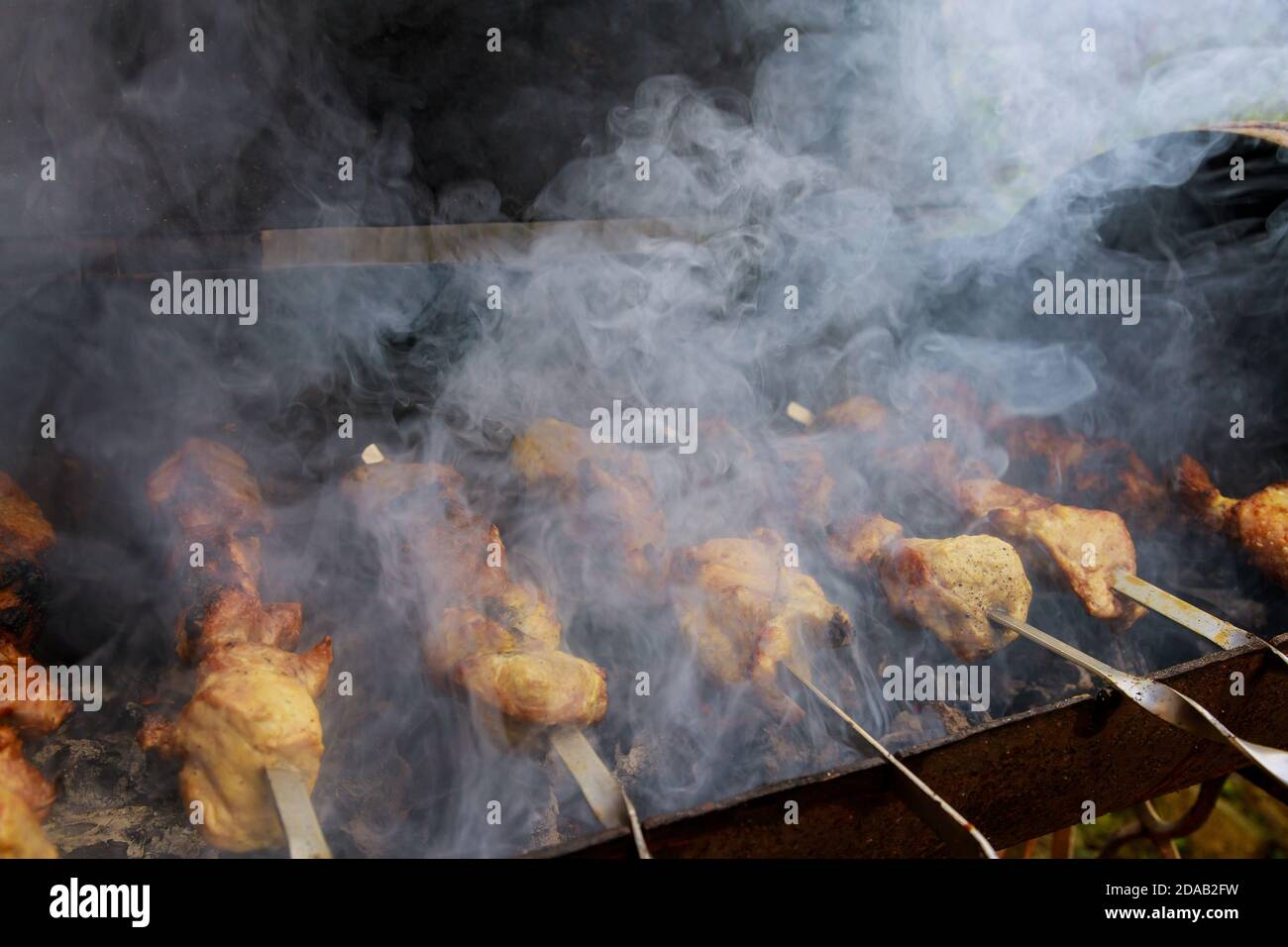 La carne affumicata sugli spiedini metallici è grigliata con carbone che brucia. Messa a fuoco morbida. Foto Stock