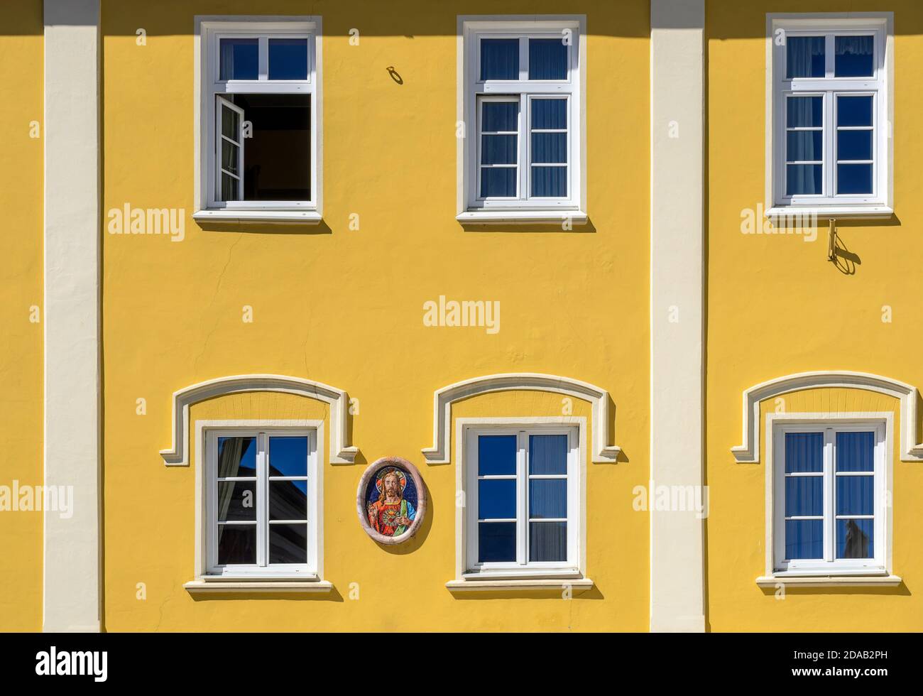 Fronte giallo di una casa borghese con immagine di gesù cristo a Lienz, Austria Foto Stock