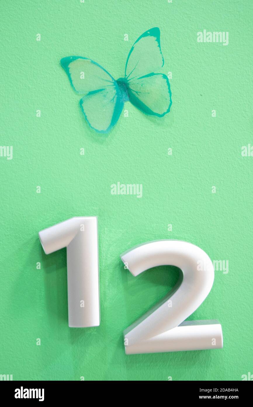 Numeri su sfondo verde con farfalla verde Foto Stock