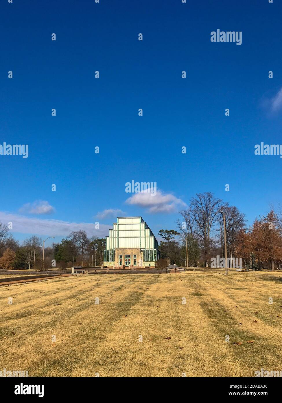 Saint Louis, MO--Dic 22, 2018; Vista di Jewel Box verde casa e giardino botanico nel parco forestale con cielo blu e campo in primo piano in inverno Foto Stock