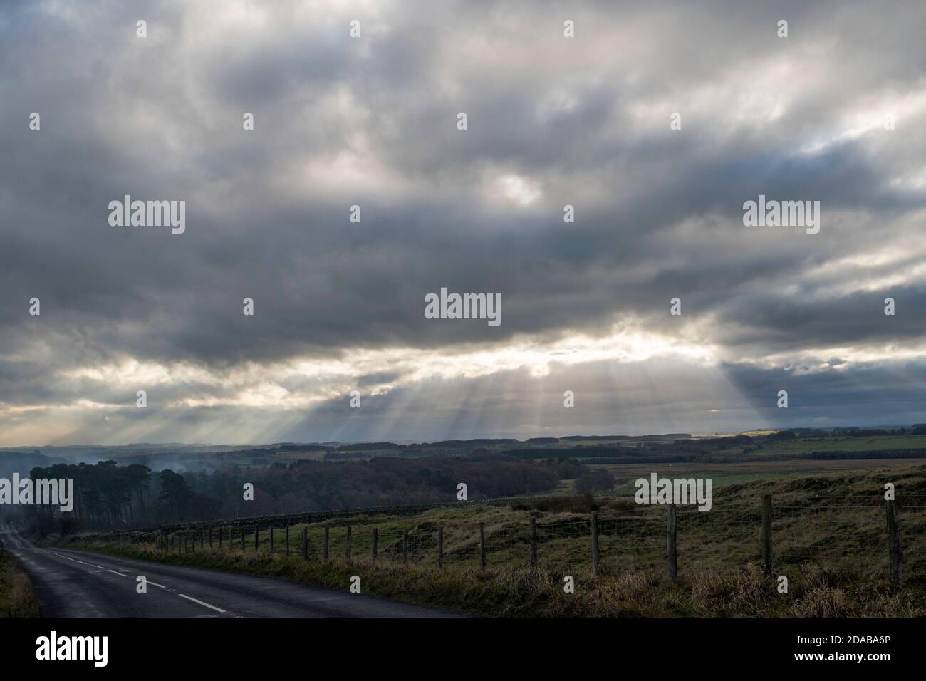 Cieli scuri e raggi solari che attraversano sopra le brughiere a sud di Rothbury, nel Northumberland, Inghilterra, Regno Unito Foto Stock
