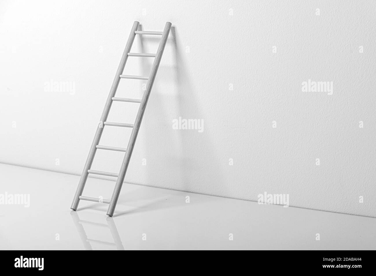 Scala di legno vicino al muro in una stanza bianca vuota Foto Stock