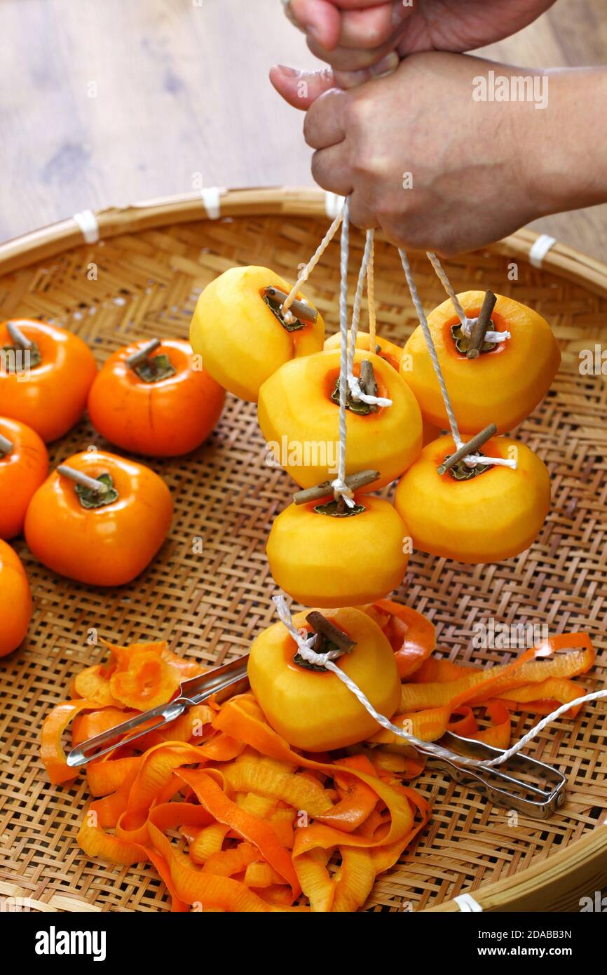 Come fare i persimmons secchi giapponesi ( Hoshigaki ); preparandosi ad appendere i frutti di persimmon. Foto Stock
