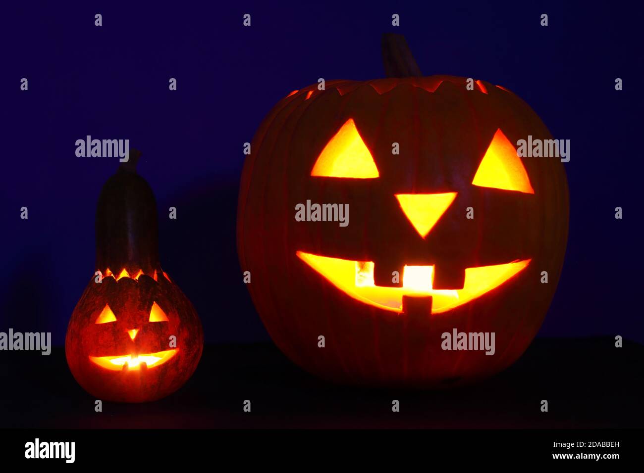 Due zucche con facce intagliate per Halloween, sfondo blu scuro Foto Stock