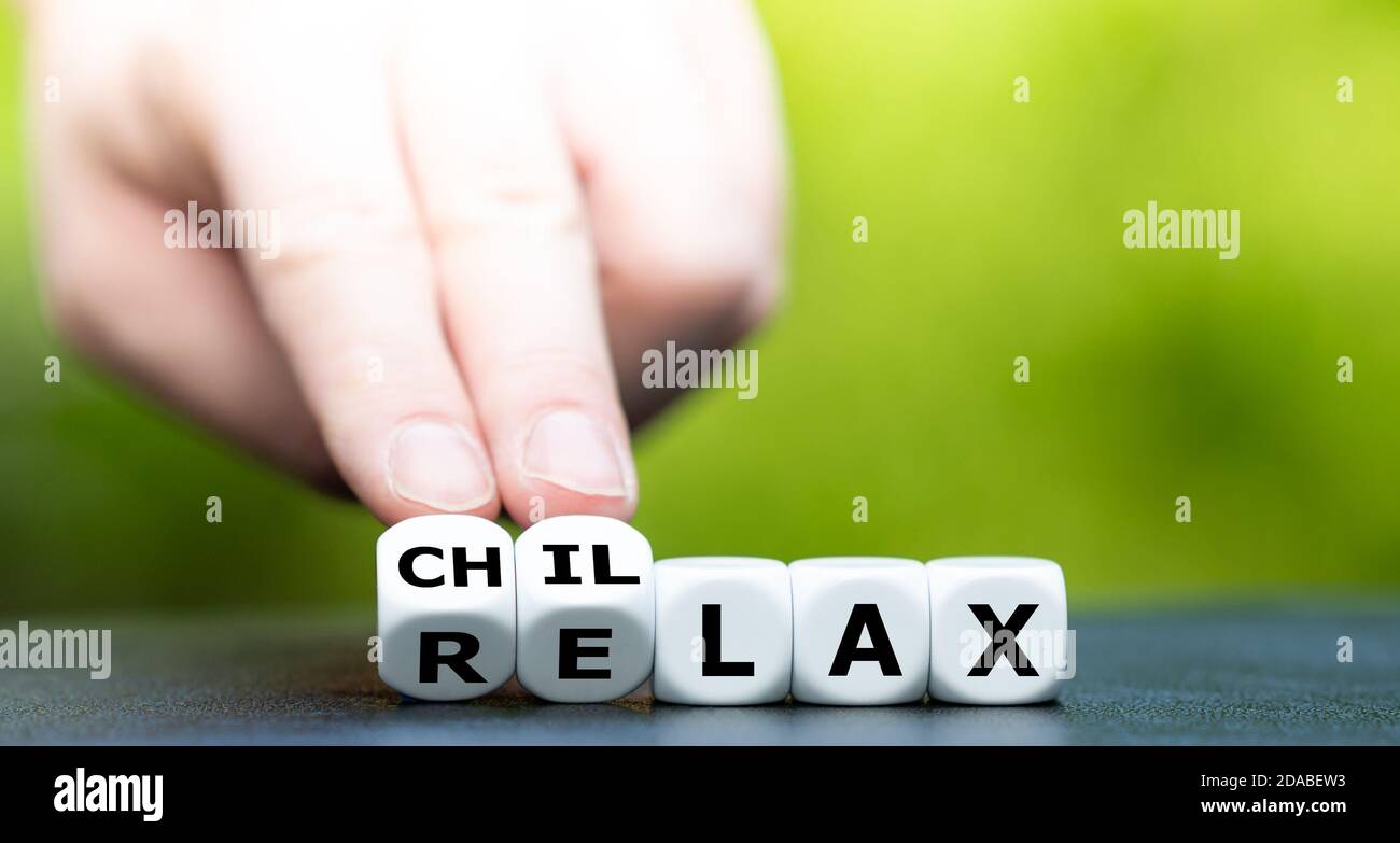 La mano trasforma i dadi e cambia la parola "relax" in "chillax". Foto Stock