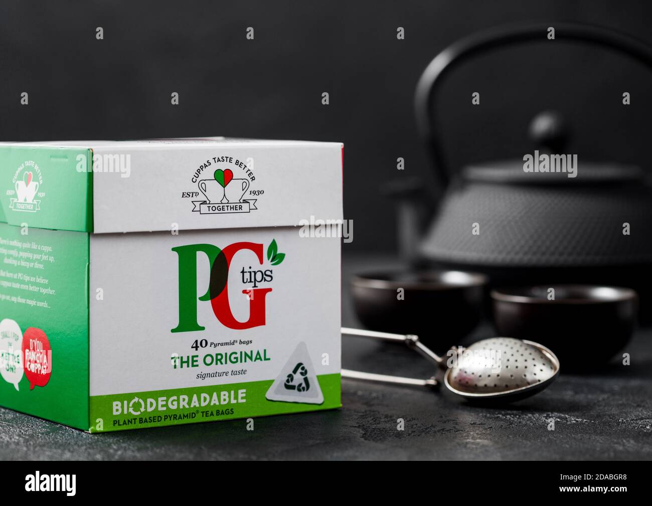 LONDRA, UK - 21 OTTOBRE 2020: Confezione di PG suggerimenti tè nero con teiera in ferro e setaccio vintage infuser su sfondo nero. Foto Stock