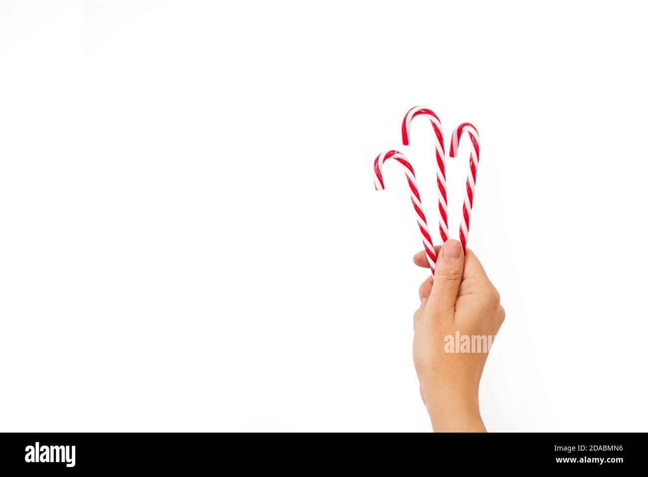 Donna mano che tiene tre canne caramelle su uno sfondo bianco e con spazio per la copia Foto Stock