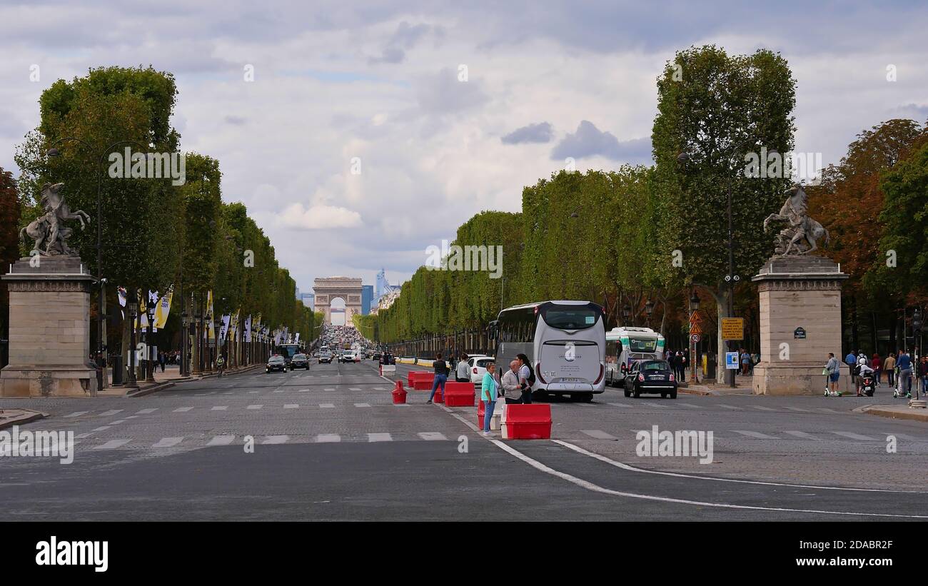 Parigi, Francia - 09/07/2019: Vista frontale della strada trafficata Avenue des Champs-Elysees incorniciata da alberi tagliati con traffico pesante. Foto Stock