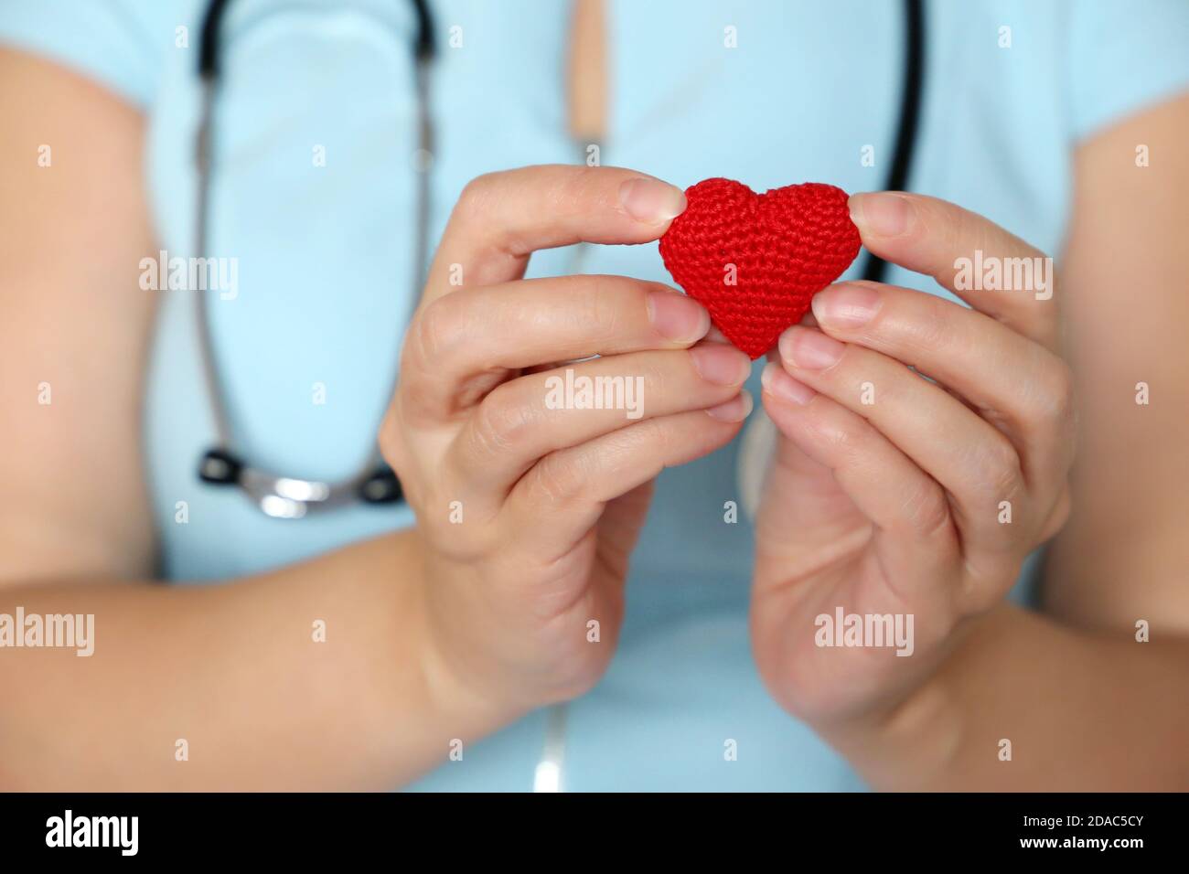 Salvare vite umane durante una pandemia di coronavirus del covid-19, medico della donna che tiene il cuore lavorato a maglia rosso nelle mani Foto Stock